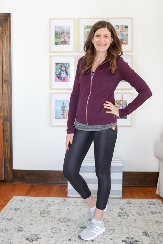 woman wearing blackberry wine colored contour zip-up jacket and shiny black leggings from Wantable Active Edit