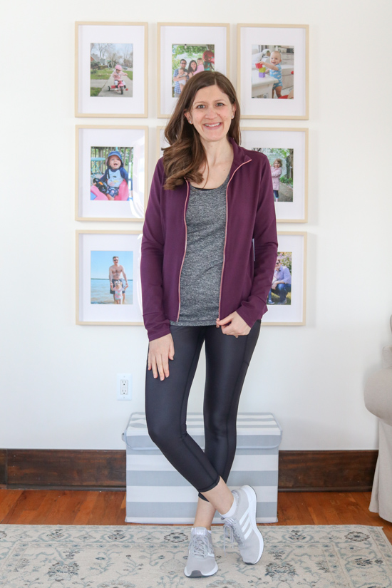 woman wearing blackberry wine colored contour zip-up jacket, gray workout tank, and shiny black leggings from Wantable Active Edit