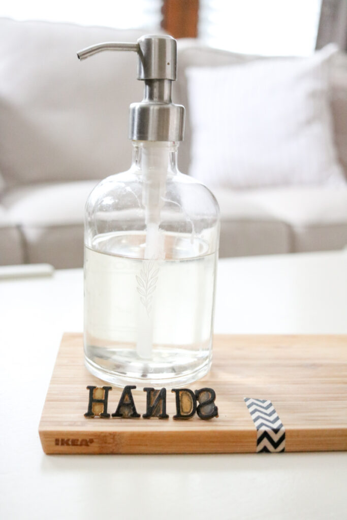clear glass hand soap dispenser for kitchen with woodburning stamps that spell HANDS