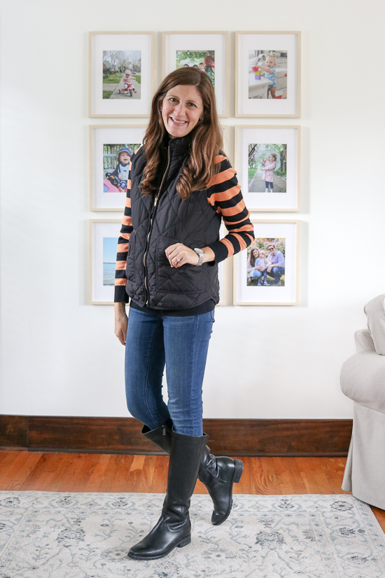 Amazon Essentials black and orange stripe Lightweight Mockneck Sweater with jeans, a black puffer vest, and black riding boots